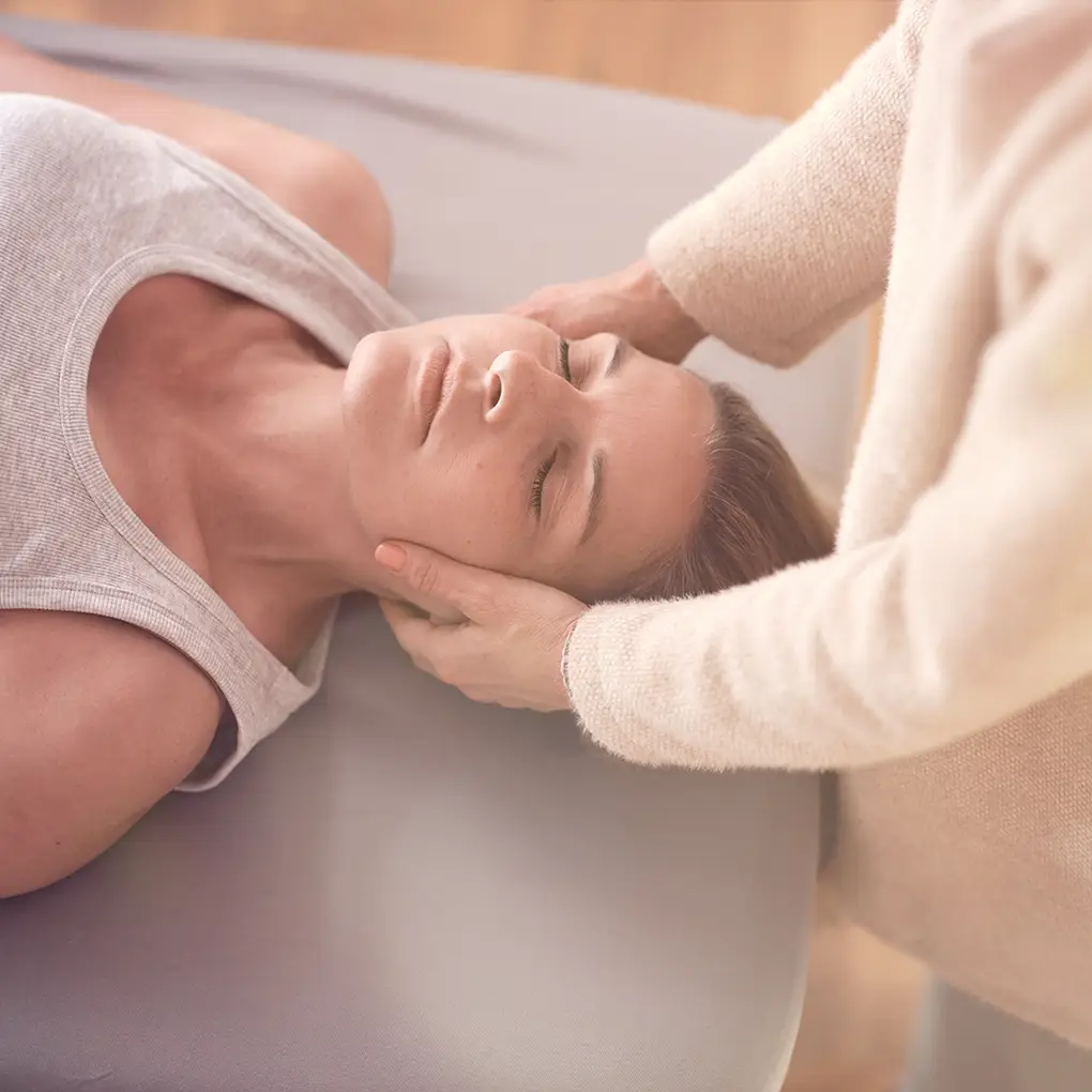 Janna Raphaela Odesser hält sanft den Kopf einer liegenden Patientin und unterstützt sie in einer körperorientierten Entspannungs- und Wahrnehmungsarbeit – achtsame therapeutische Begleitung in ruhiger Atmosphäre