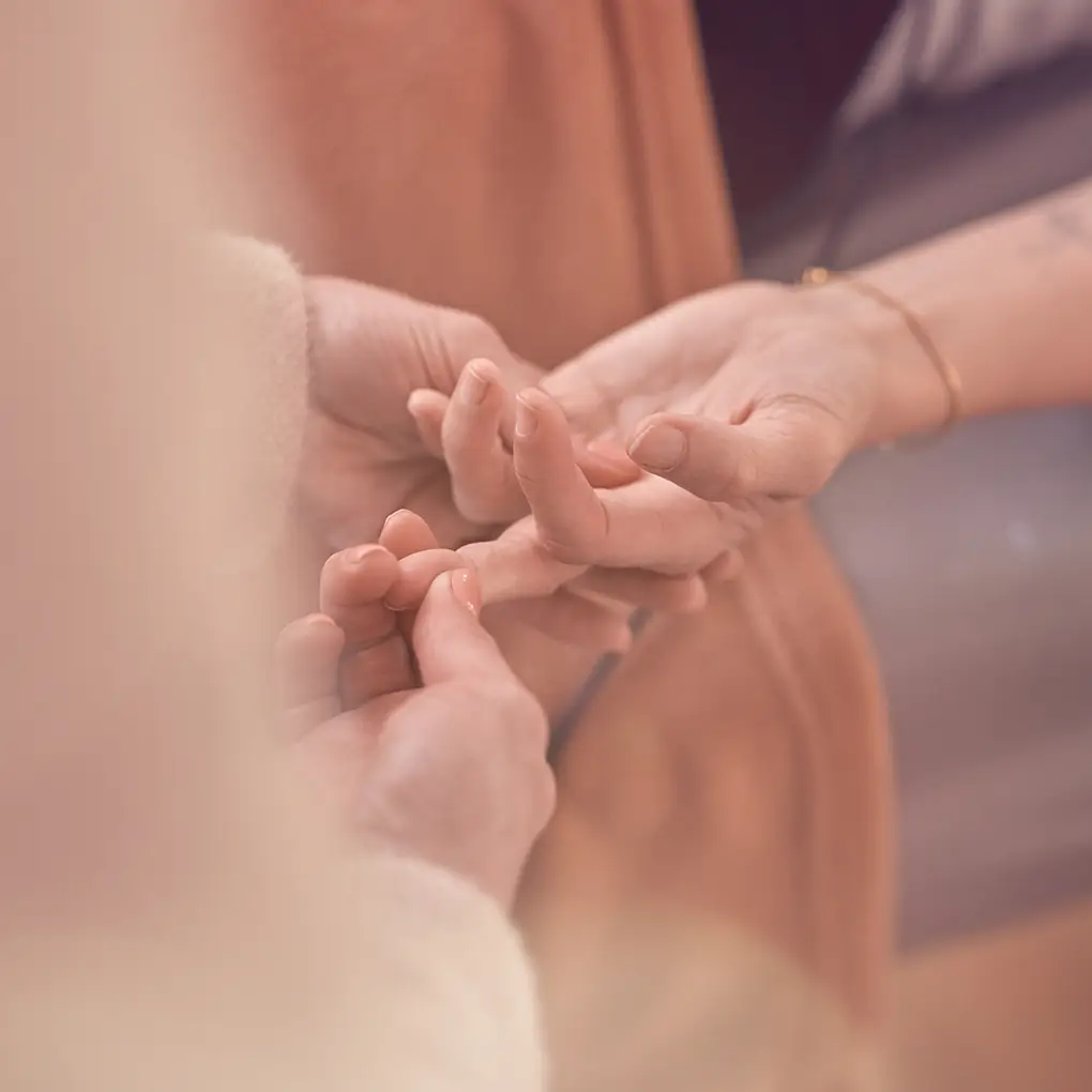 Janna Raphaela Odesser hält behutsam die Hand einer anderen Person als Geste von Achtsamkeit und Verbindung