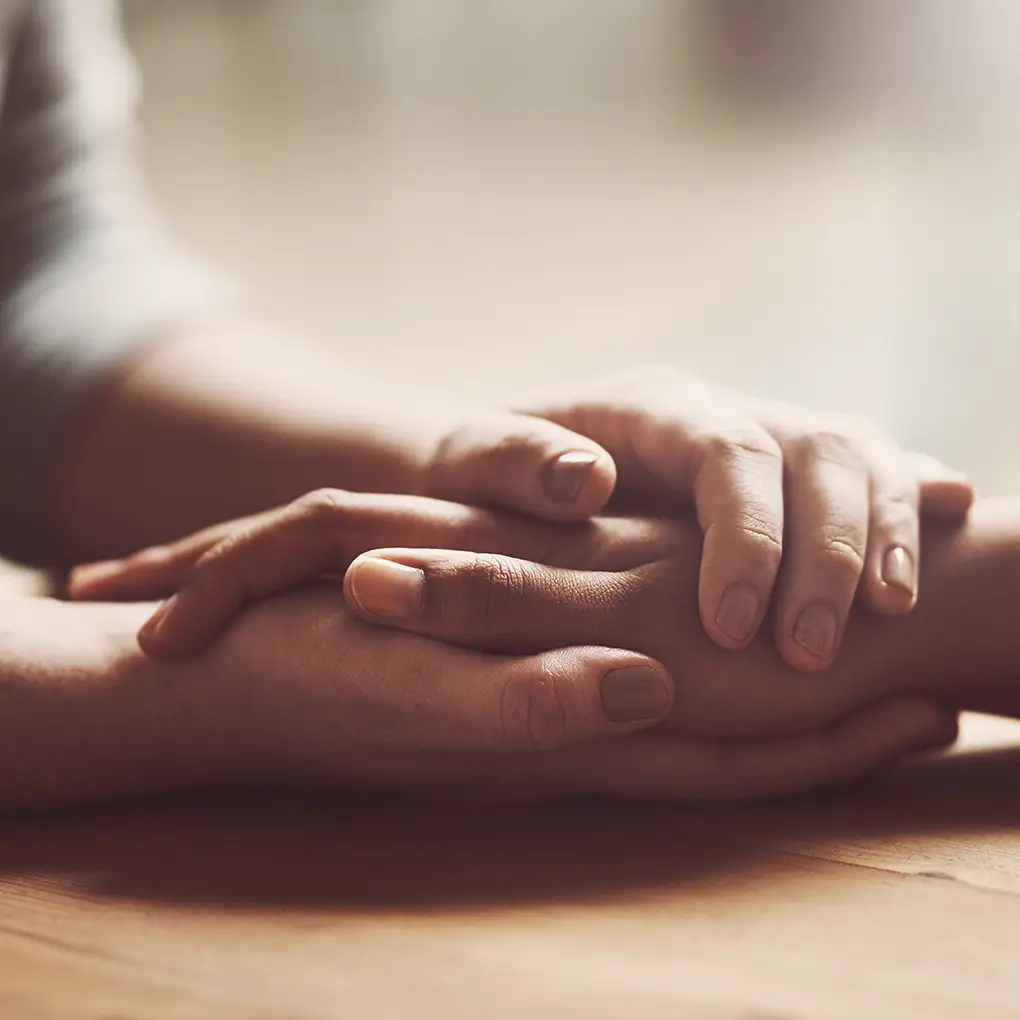 Zwei Menschen halten einander die Hände als Geste von Trost und Unterstützung